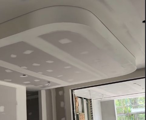 A curved bulkhead formed and lined in a ceiling, set and sanded, running out to the window.