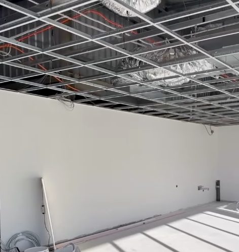 A commercial fit out with the walls sheeted and set below an open ceiling grid and the services above it.