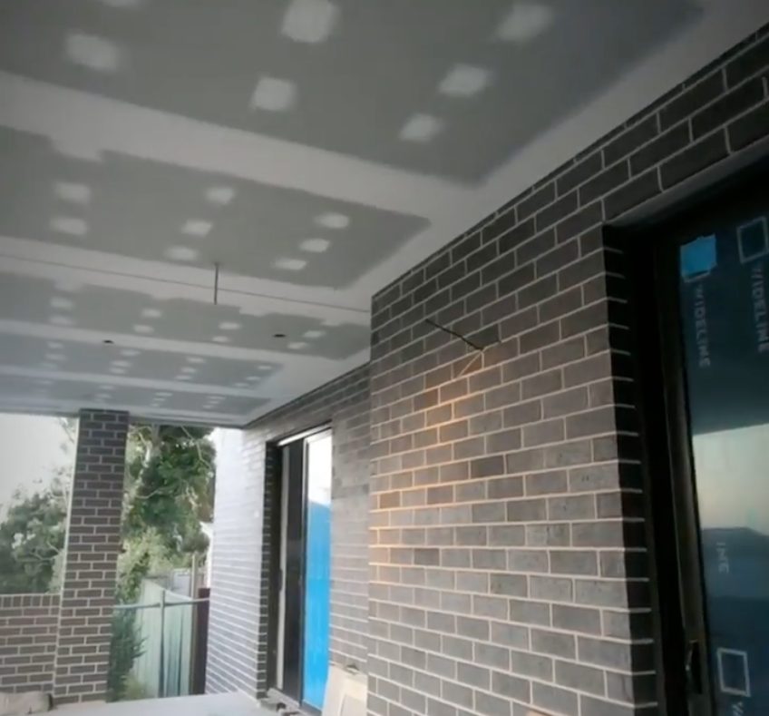The ceiling of an existing patio roof lined and set, running back to the brickwork and the glass doors.